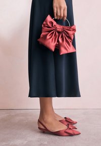 Rdeče satenske slingback balerinke z mašnim okrasom, združene z ujemajočo se rdečo satensko torbico z mašno in kovinsko ročico. Temno teksturirana krilo.