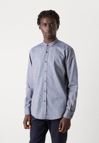 Hosszú ujjú gombos ing világoskék chambray anyagból, álló gallérral és kék gombokkal, kényelmes szabással és egyetlen mandzsettával.