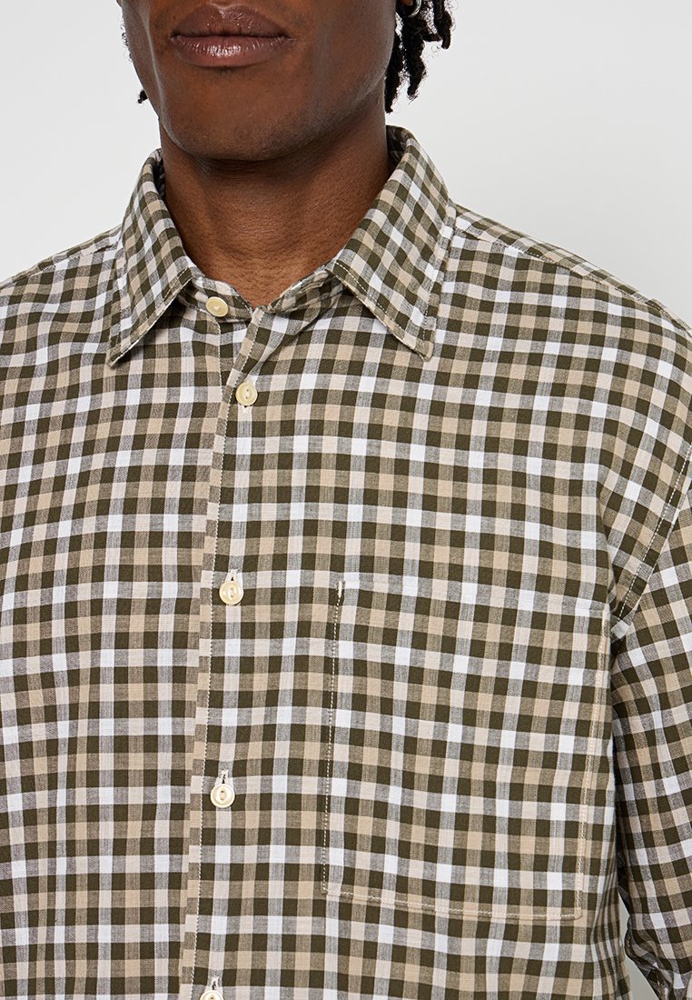 Bruin en wit geruit overhemd met knopen, voorzien van een klassieke kraag, borstzak en lichtgestoffeerde stof met zichtbare stikseldetails.