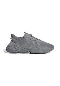 Sneakers atletici grigi con materiali in rete e scamosciato. Presentano una suola spessa, elementi di design ondulati e sottili accenti testurizzati.
