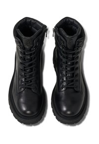 Černé kožené kotníkové boty mají texturovaný povrch, polstrovaný límec, šněrování v přední části a boční zip. Gumová podrážka zvyšuje přilnavost a odolnost.