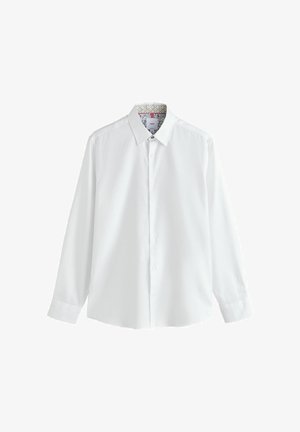 Chemise blanche à manches longues avec un col boutonné. Texture lisse et doublure colorée à motifs visible à l'intérieur du col.