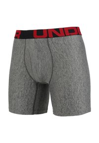 Boxers grises fabriqués en tissu doux et texturé, dotés d'une taille noire avec les lettres rouges « UNDER » et d'une poche frontale stylisée.