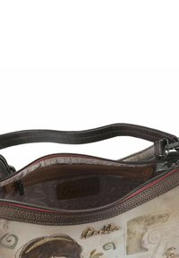 Handtasche mit einer strukturierten braunen Lederaußenfläche, einem hell gemusterten Innenfutter und Reißverschluss. Auffällige Details sind ein Logoanhänger und dekorative Akzente.