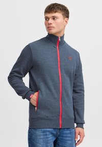 Dunkelgrauer Reißverschluss-Sweatshirt mit rotem Reißverschluss, hohem Kragen und Seitentaschen. Weicher Stoff mit gerippten Bündchen und einem Logo auf der Brust.