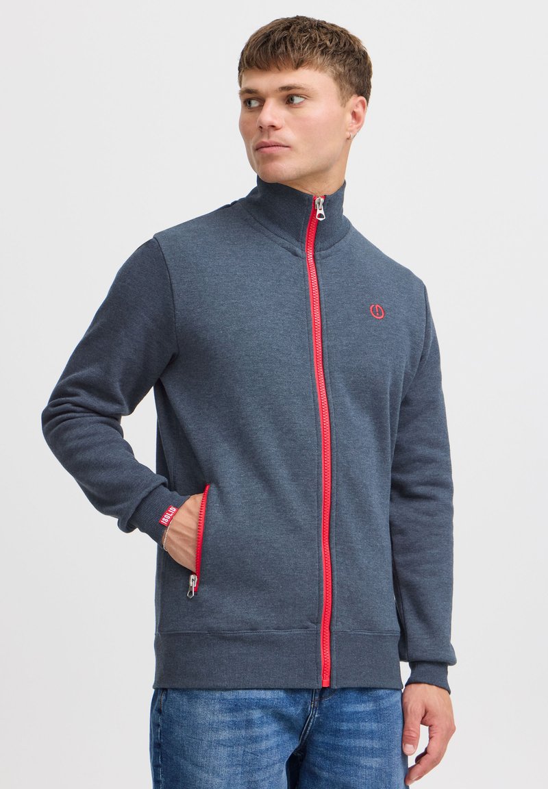 Dunkelgrauer Reißverschluss-Sweatshirt mit rotem Reißverschluss, hohem Kragen und Seitentaschen. Weicher Stoff mit gerippten Bündchen und einem Logo auf der Brust.