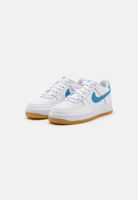 Białe skórzane sneakersy z niebieskim swooshem, płaskimi sznurówkami i perforowaną cholewką na palce. Posiada gumową podeszwę zewnętrzną dla lepszej przyczepności.