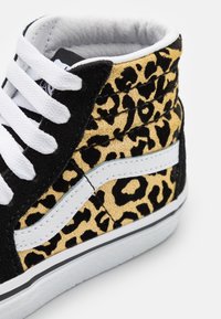 Černé a zlaté vysoké tenisky s leopardím potiskem, bílé tkaničky a bílý boční pruh. Měkký materiál s texturovanými akcenty.