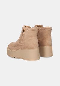 Botas de tobillo beige hechas de suave ante con un acabado texturizado, que cuentan con una cremallera lateral y una suela gruesa y robusta.