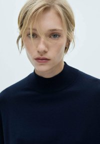 Pulover pe gât de culoare bleumarin, realizat dintr-un material tricotat moale, cu un guler aderent și un design minimalist. Textură netedă, fără modele vizibile.