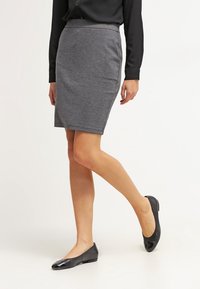 Grijze aansluitende pence-skirt van zachte stof, met een gladde textuur en een elastische tailleband, gecombineerd met zwarte ballet flats.