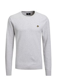 Ljusgrå tröja med lång ärm, texturerat tyg, rund halsringning och en liten gul emblem på vänstra bröstområdet.