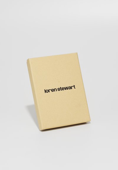Barna kartondoboz minimalista dizájnnal; az elején fekete nyomtatott szöveg található: "loren stewart". Simább textúra, téglalap alakú.
