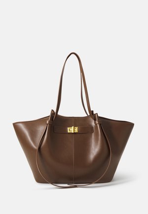 Borsa tote in pelle marrone con doppi manici, chiusura rettangolare dorata e forma trapezoidale ampia su sfondo neutro.
