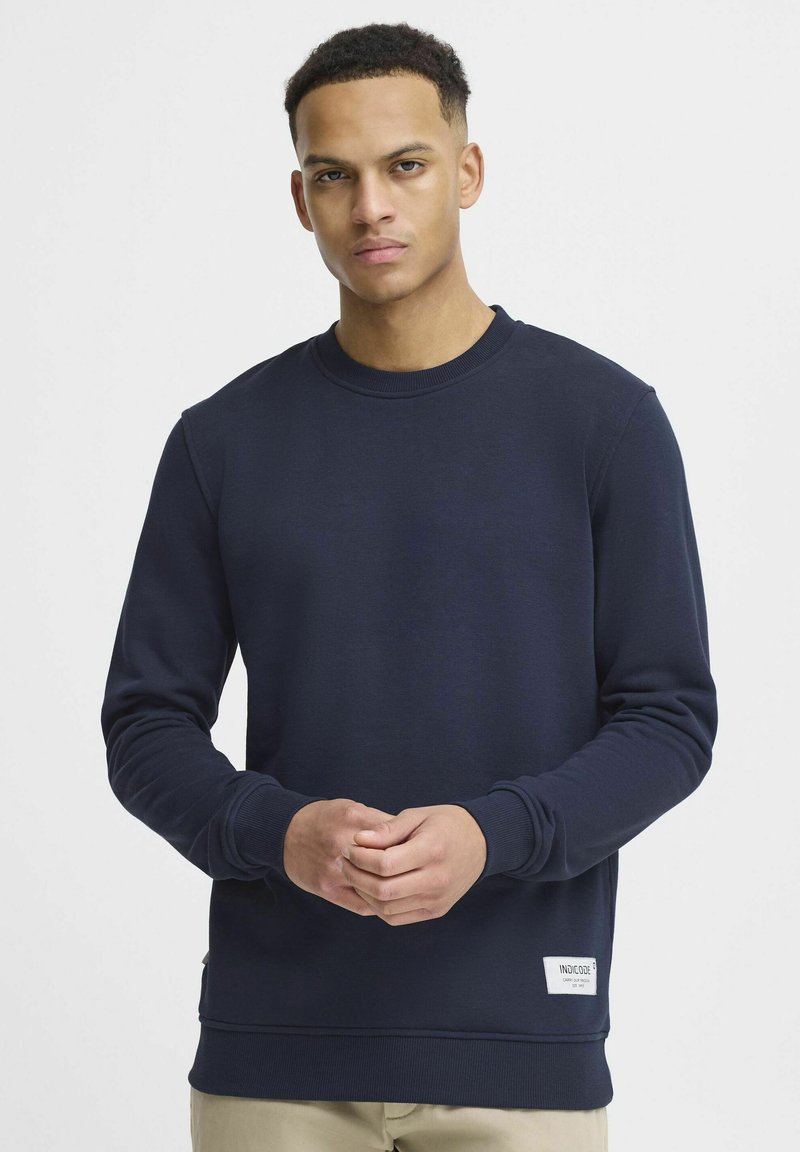 Navy blue sweatshirt in a soft fabric with a ribbed crew neckline and cuffs; features a label on the lower left side.