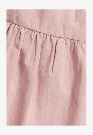 Tessuto rosa chiaro con una morbida texture, caratterizzato da dettagli arricciati in vita e leggere pieghe, che creano profondità nel design.