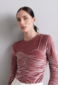 Samtoberteil mit langen Ärmeln in staubigem Rosaton, mit geraffter Textur an der Brust und elastischen Trägern für eine optimale Passform, kombiniert mit einem schlichten Design.