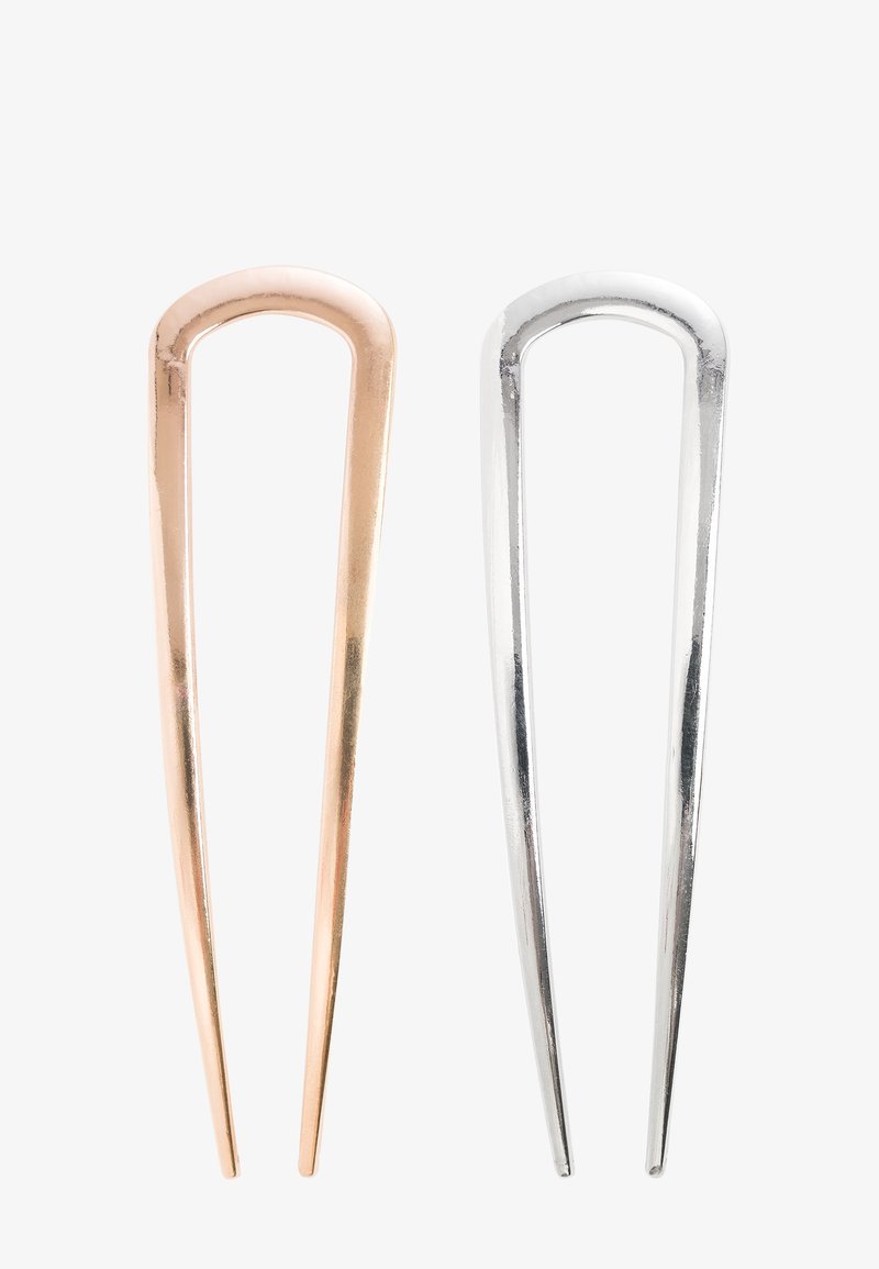 Två minimalistiska U-formade metallhårnålar, en roséguld och en silver, visas sida vid sida på en vit bakgrund.