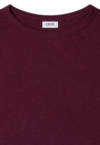 Camiseta burdeos de cuello redondo con costuras visibles y una etiqueta de marca blanca "CECIL" cosida en el interior del cuello.