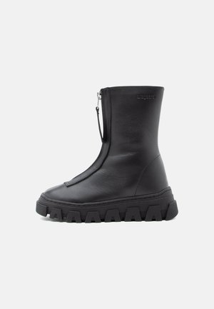 Sorte lær ankelstøvlett med en kraftig teksturert såle, sidelukking med glidelås og glatt overflate. Minimalistisk design uten synlig merke.