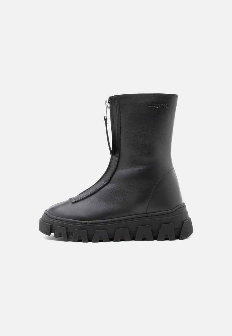 Bottine en cuir noir avec une semelle texturée épaisse, fermeture éclair sur le côté et finition lisse. Design minimaliste sans logo visible.