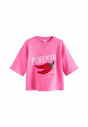 Jasnoróżowa bluza z krótkim rękawem z napisem "PIMENTO" oraz dwoma czerwonymi grafikami chili na przodzie.