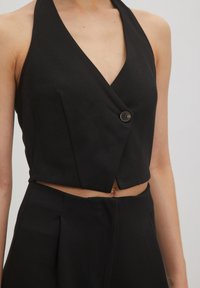 Zwarte cropped haltertop met V-hals, enkele knoopsluiting en een opvallende textuur. Heeft een op maat gemaakte ontwerp met een getailleerde silhouet.