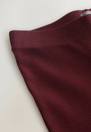 Bordo spalvoto ribuoto audinio leggingai su lygiu juosmeniu, turinčiu subtilią horizontalią tekstūrą ir tvarkingą siuvimą kraštuose.