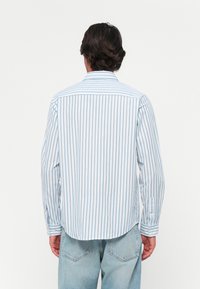 Light blue and white striped long-sleeved shirt with a button-down collar. Features a curved hem and single-button cuffs. Casual fit.