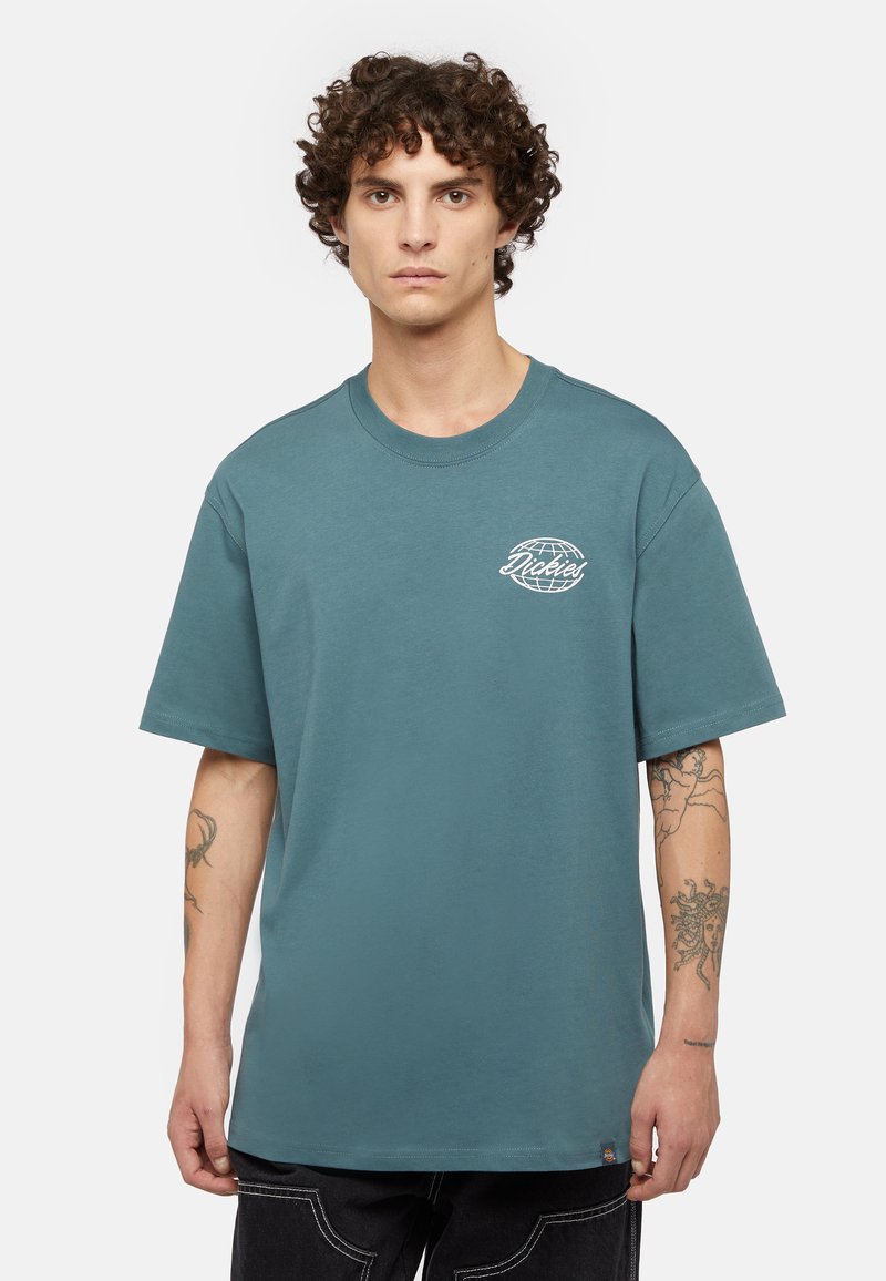 T-shirt en coton teal avec un col rond et des manches courtes ; présente un logo imprimé en blanc sur la poitrine gauche et une petite étiquette de marque à l'ourlet.