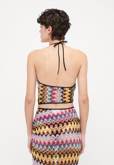 Virkat halterneck med ett flerfärgat zigzag-mönster. Har en svart knytning i nacken och en figurnära design, ihop med en matchande kjol.