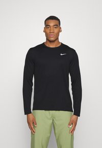 Czarna longsleeve t-shirt z gładkiego materiału, z małym białym logo Nike na lewej piersi i okrągłym dekoltem.