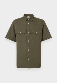 Chemise à manches courtes en tissu vert olive. Elle comporte deux poches poitrine, un col classique et une fermeture à boutons sur le devant avec des boutons blancs.