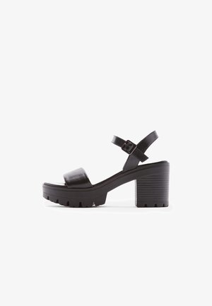 Zwarte haksandalen met een chunky platform, zachte lederen banden, verstelbare enkelgesp en gestructureerde ribbelblokhak.