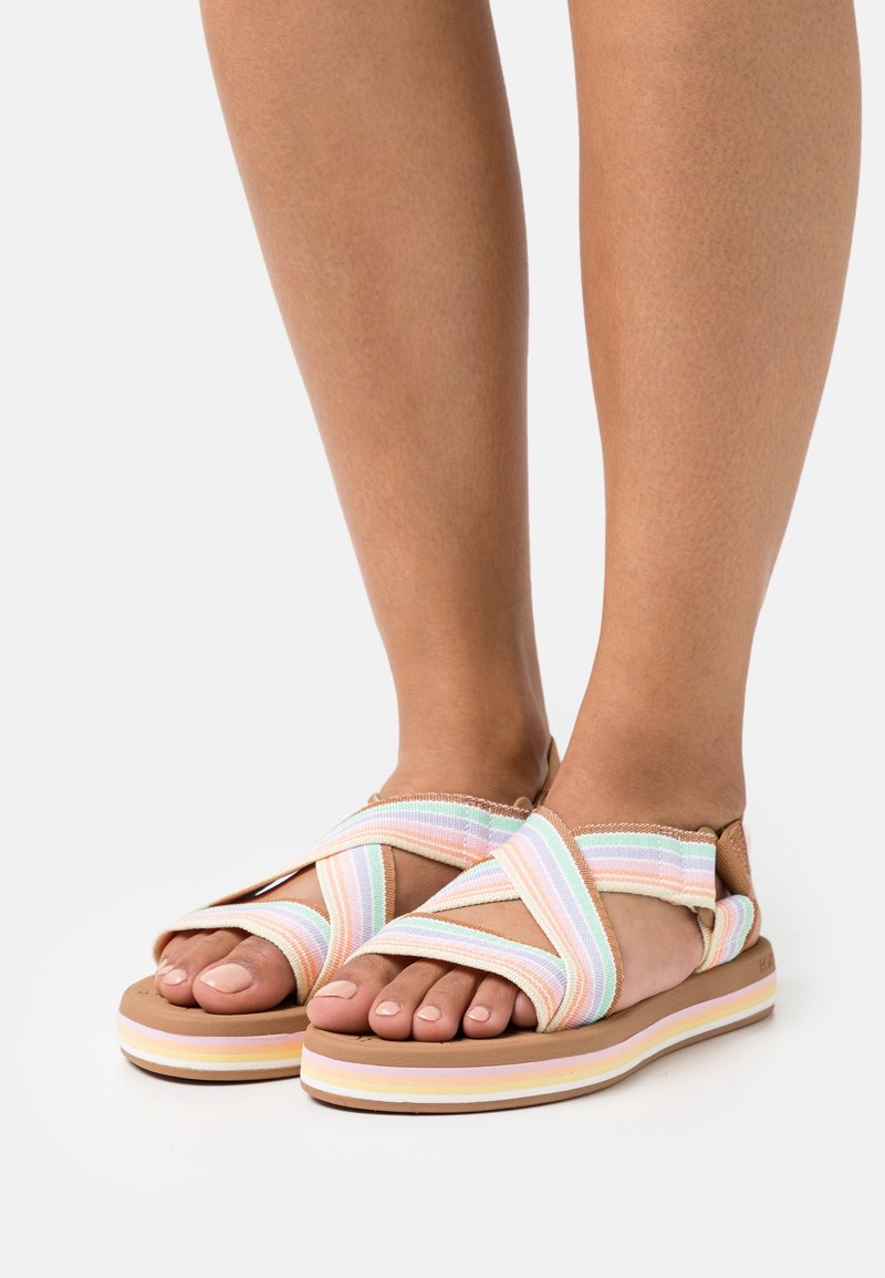 Sandali incrociati realizzati in tessuto intrecciato a righe pastello, con una suola testurizzata e imbottita dai colori sovrapposti di marrone, rosa e crema.