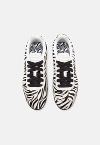 Baskets à motifs zèbre noir et blanc avec une tige texturée, des lacets noirs et une semelle intérieure à motif. Bout arrondi et semelle en caoutchouc plate.