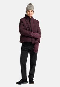 Giacca a vento viola, berretto in maglia grigia con pompon, guanti in maglia viola, pantaloni neri e scarpe nere. Caratteristiche del design trapuntato.