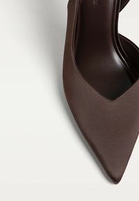 Hnědá vysoká boty na podpatku s špičatým designem. Vyrobeno z hladké látky, má elegantní, minimalistický siluetu a žádné viditelné kovové prvky.