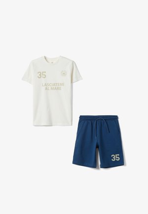 Camiseta blanca de manga corta con el texto "35" y "LASCIATEMI AL MARE", combinada con pantalones cortos azules con cordón que llevan el número "35".