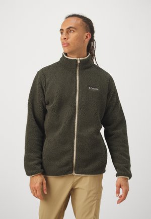 Chaqueta de forro polar verde oliva con un acabado texturizado, cuello alto, cierre de cremallera y ribete color beige claro. Presenta el logotipo de Columbia en el pecho.