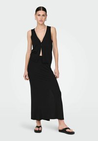 Completo due pezzi nero composto da un top senza maniche con scollatura a V profonda e una lunga gonna fluida. Tessuto liscio con design elegante.