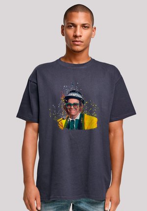Dark gray T-shirt featuring a colorful graphic print of a person in a yellow outfit with a green tie, hat, glasses, and a microphone.