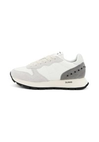Witte en grijze sneaker van suede en leer, met een dikke zwarte zool en decoratieve gaten op het grijze hielgedeelte.
