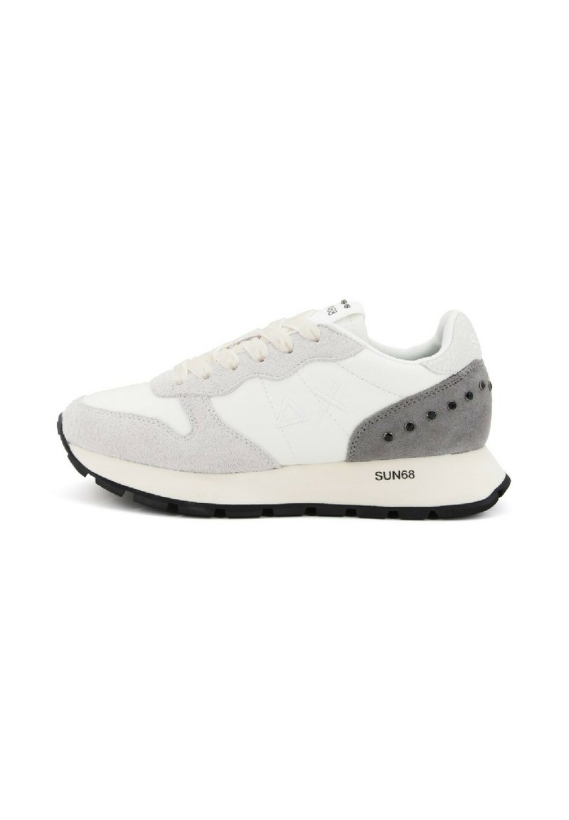Witte en grijze sneaker van suede en leer, met een dikke zwarte zool en decoratieve gaten op het grijze hielgedeelte.