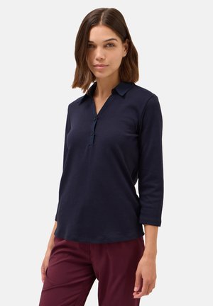 Donkerblauwe, langarm polo met een knoopsluiting bij de kraag en een gladde textuur, gecombineerd met bordeauxrode broek. Eenvoudig en modern ontwerp.