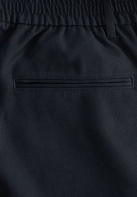 Pantalon en tissu noir avec une ceinture élastique, une poche horizontale fendue et une boucle de ceinture sur le bord supérieur.