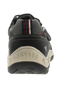 Baskets noires et grises avec une tige en cuir texturé, un accent en tissu rayé et une semelle en caoutchouc blanc comportant un logo "MUSTANG" en relief.