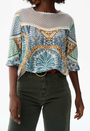 Geprinte blouse met korte mouwen; heeft blauwe, groene en gouden patronen; doorzichtige stippen yoke; ingewikkelde bloemmotieven; ontspannen pasvorm.