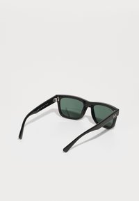Svarta rektangulära solglasögon med gröna linser, glänsande båge och tjocka stänger. Har Ray-Ban-logga på sidan och metallaccenter.