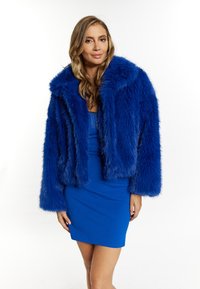 Faux fur jas in levendig blauw, cropped ontwerp met een brede kraag en lange mouwen. Draag het over een bijpassende blauwe, getailleerde jurk.